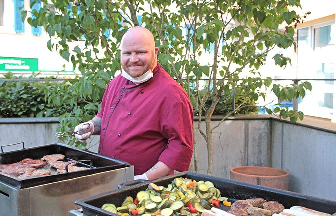 Grillender Mann bereitet Fleisch und Gemüse im Garten der Tagespflege