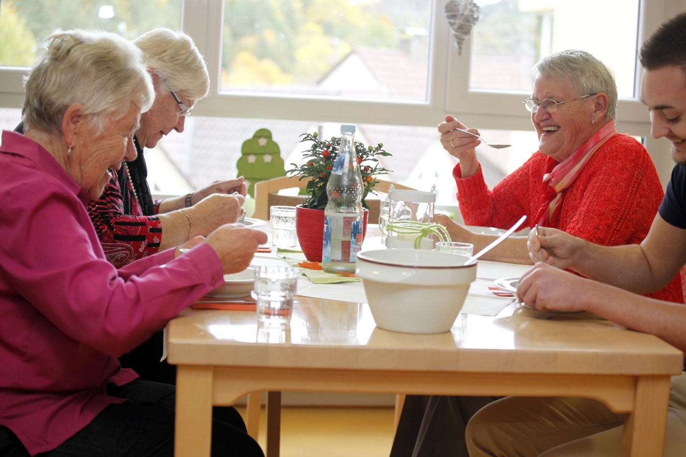 Seniorinnen und ein junger Mann beim gemeinsamen Mittagessen