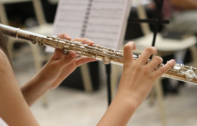Hände spielen Querflöte beim Abschlusskonzert vor Notenblatt