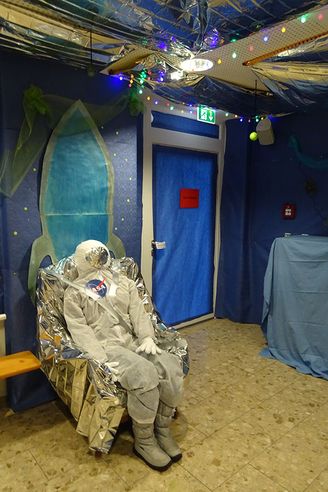 Schaufensterpuppe in Raumanzug mit NASA Logo auf Folienstuhl