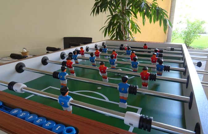 Multi-Spieltisch mit roten und blauen Kickerfiguren und Zählsteinen
