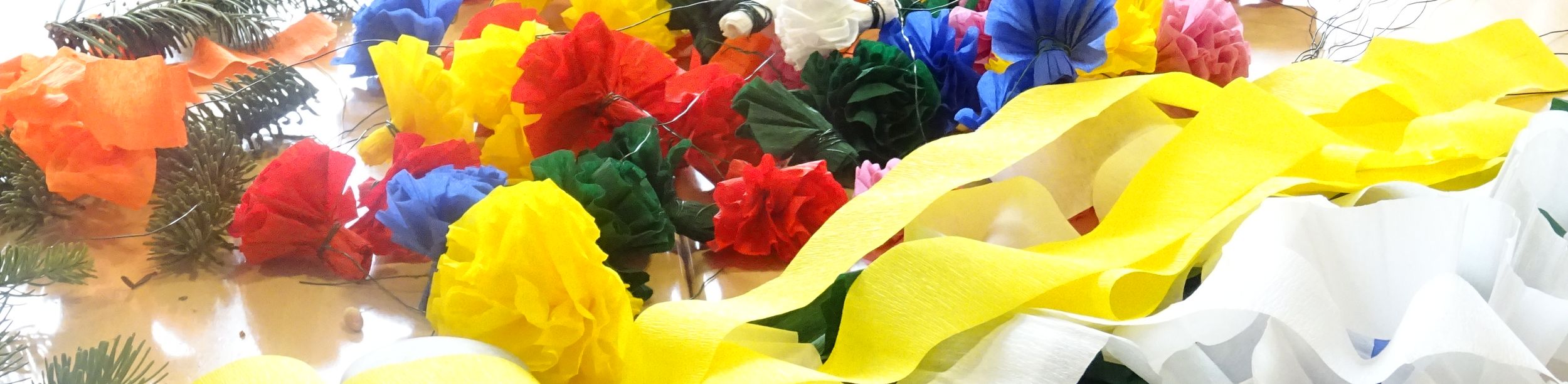 Basteltisch mit bunten Krepppapierblumen Zweigen und Schere in Tagespflege