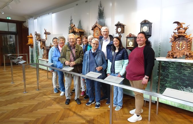 Gruppe von Museumsbesuchern vor antiken Kuckucksuhren