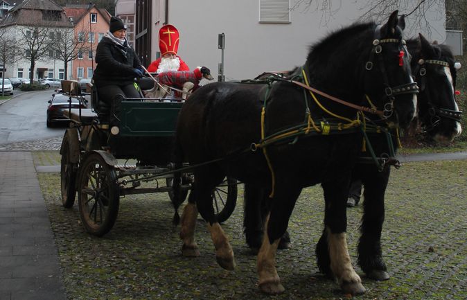 Nikolaus in rotem Bischofsgewand auf Pferdekutsche durch Ort
