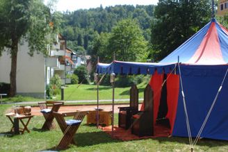 Blaues und rotes Mittelalterzelt mit Holzthronen und Klappstühlen