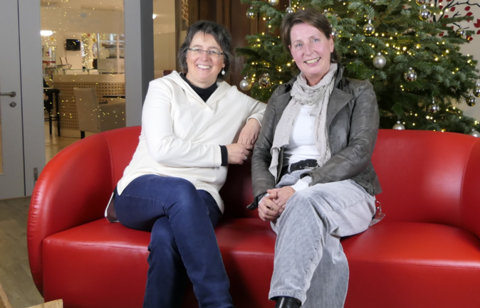 Einrichtungsleitung zu Besuch auf rotem Sofa vor Weihnachtsbaum