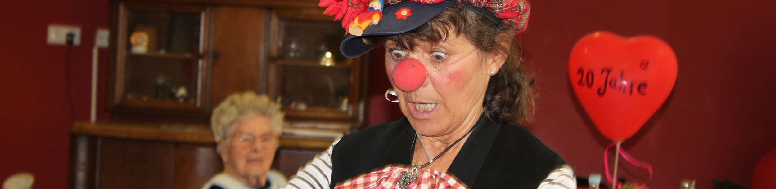 Clownin mit roter Nase und kariertem Hut öffnet Flasche