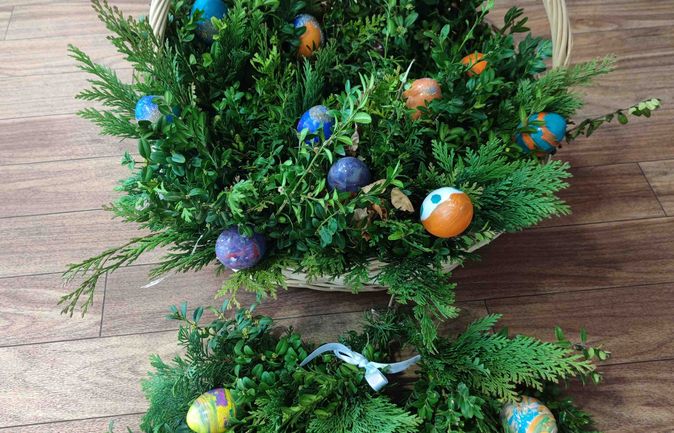 Osterliche Palmbüschel im Korb aus Buchs und Tannengrün mit bemalten Eiern