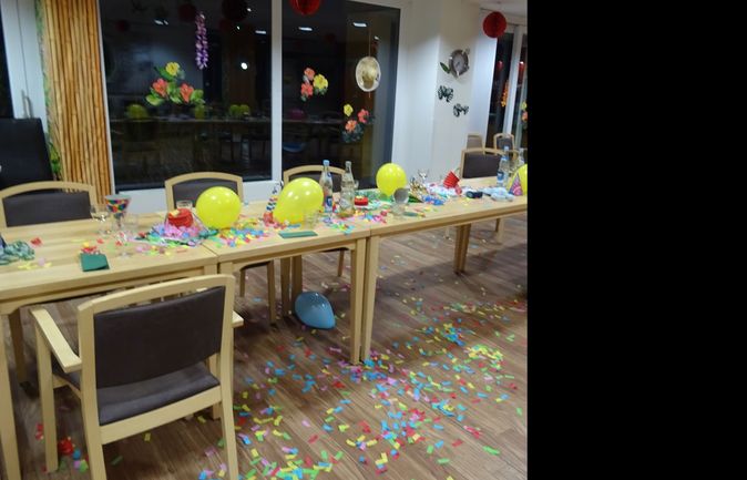 Leerer Partytisch mit gelben Ballons, Flaschen und Konfetti