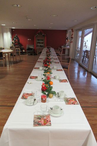Langer festlich gedeckter Tisch mit Weihnachtsdekoration und Kaffeegedecken