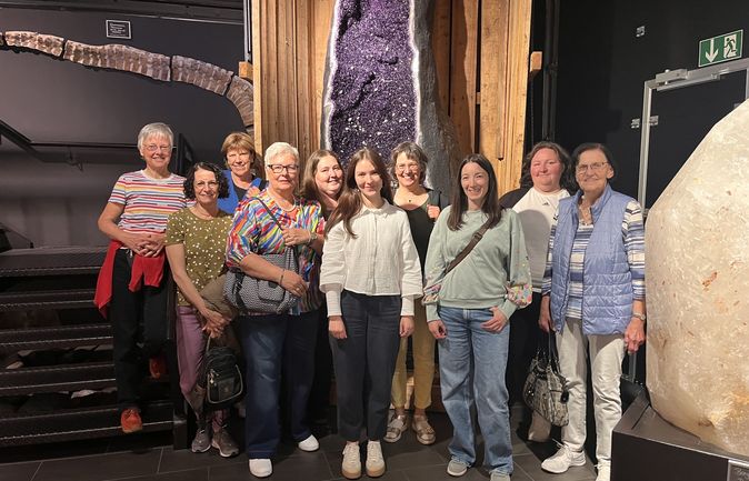 Gruppe von Ehrenamtlichen vor großer violetter Kristallgrotte
