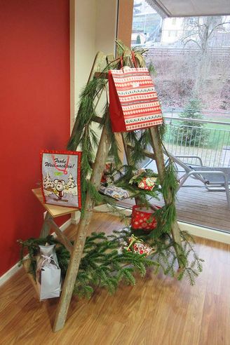 Geschmückte Holzleiter mit Tannenzweigen und Weihnachtsgeschenken