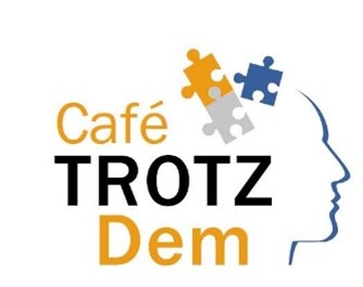 Schriftzug Café TROTZ Dem neben blauem Kopfprofil mit drei Puzzleteilen